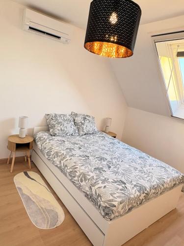 een slaapkamer met een bed en een kroonluchter bij Le cocon auvergnat in Lapalisse