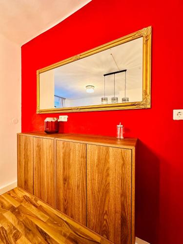 a mirror on a red wall with a wooden cabinet at Red Room in Schottwien