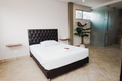a bedroom with a large white bed with a black headboard at Hotel El Descanso in Fusagasuga