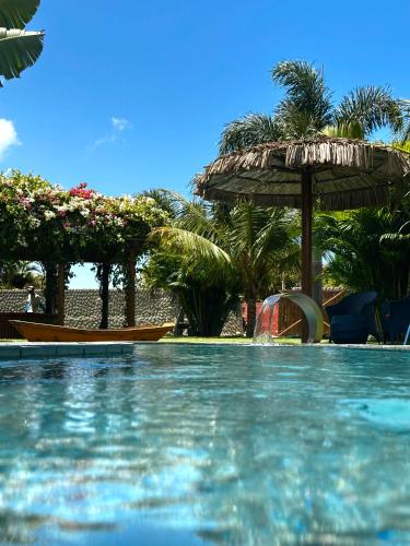 a swimming pool with an umbrella and a water slide at Pousada Solarium de Gostoso in São Miguel do Gostoso