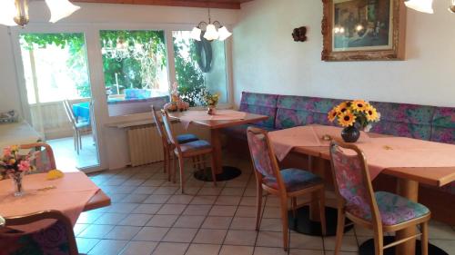un restaurante con mesas y sillas con flores. en Landhaus Irma, en Bad Füssing