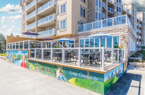 a restaurant with tables and umbrellas in front of a building at Living Water Resort & Spa in Collingwood