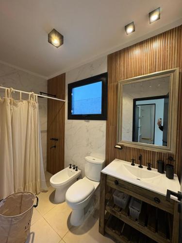 a bathroom with a toilet and a sink and a mirror at Casa Calma Cariló in Carilo