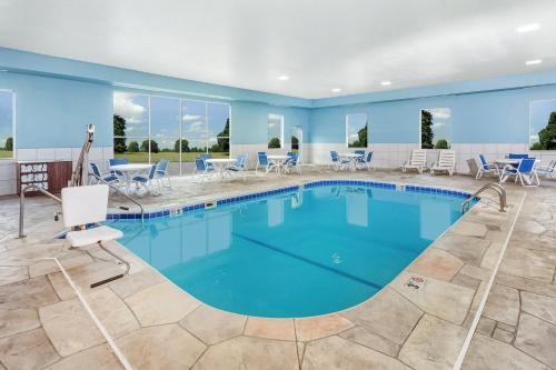 a pool in a hotel room with blue walls and chairs at Holiday Inn Express Hotel & Suites Bloomington-Normal University Area by IHG in Bloomington