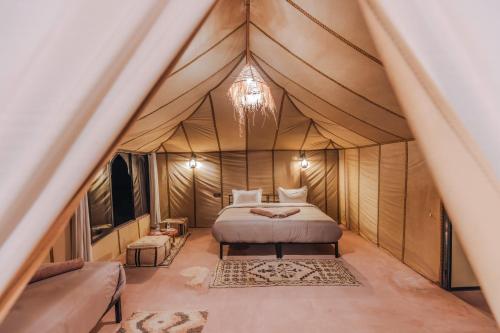 a bedroom in a tent with a bed and a couch at Luxury Camp Sahara in Merzouga