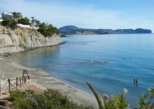 a beach with people swimming in the water at Apartamentos Santa Clara in Calpe