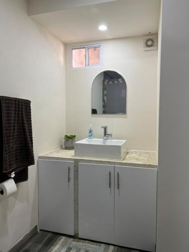 a white bathroom with a sink and a mirror at Casa Axhé Rosarito in Rosarito Beach
