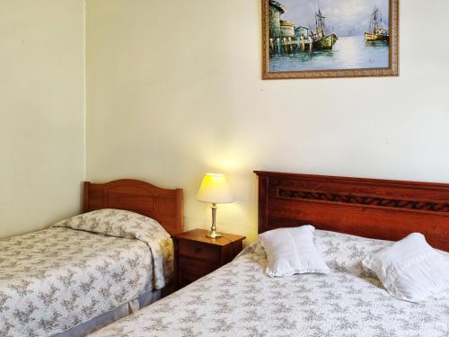 a bedroom with two beds and a picture on the wall at Hostal El Rincon Marino in Valparaíso