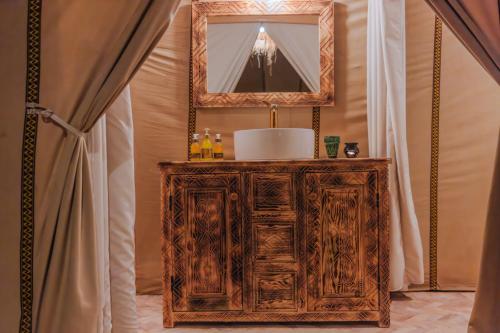 a mirror on top of a wooden cabinet in a bathroom at Luxury Camp Sahara in Merzouga