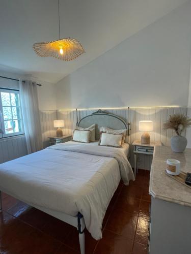 a bedroom with a large white bed with two tables at Title e Title - Alentejo in Monforte