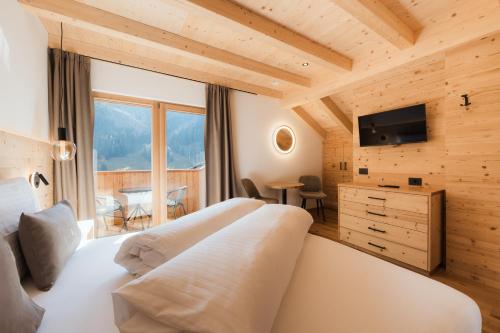 a bedroom with a large white bed and a television at Ciasa Bel Marin in La Villa