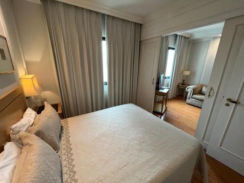 a hotel room with a bed and a living room at Flat Hotel Pamplona Jardins Univer com garagem 2402 in Sao Paulo