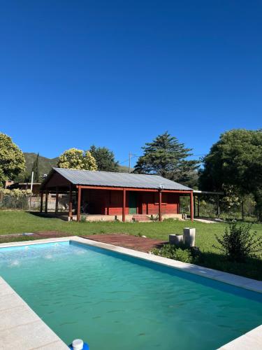 a swimming pool in front of a house at Cabañas del Valle in Huerta Grande