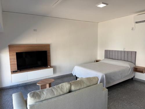 a bedroom with a bed and a tv and a couch at Studio Ikuma in Esperanza