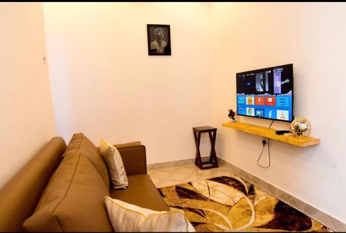 a living room with a couch and a flat screen tv at Lumora Deluxe Apartment in Tanga