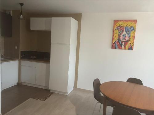 a kitchen with a table and a painting on the wall at Appartement 4 personnes rue de la mer in Ouistreham