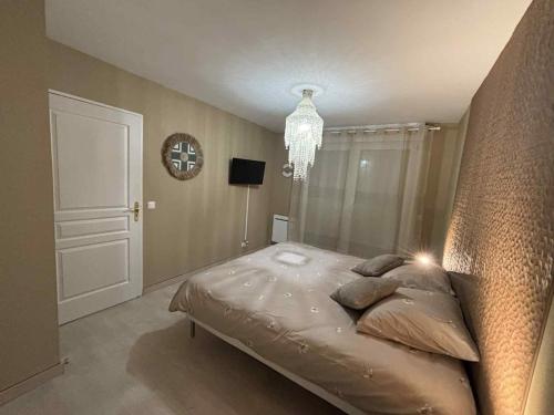 a bedroom with a large bed and a chandelier at Appartement 4 personnes rue de la mer in Ouistreham