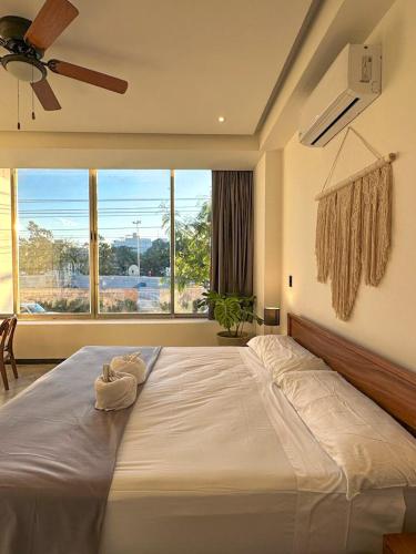 a large bed in a bedroom with a large window at Balam Suites in Playa del Carmen