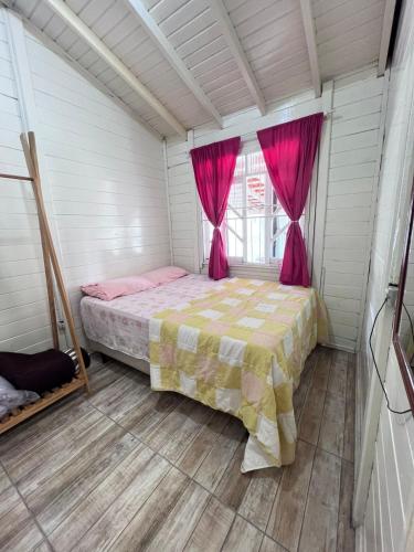 una camera con letto e finestra con tende rosa di Cantinho do Sonho - Chalé Sol a Palhoça