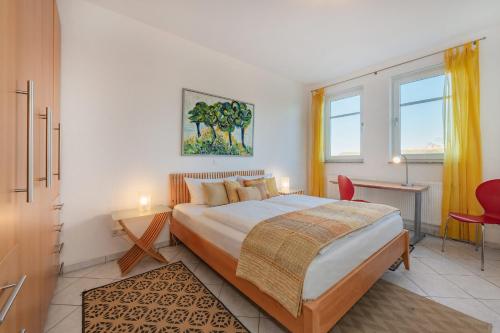 a bedroom with a large bed and a red chair at Haus Dünenwald 17 in Zinnowitz