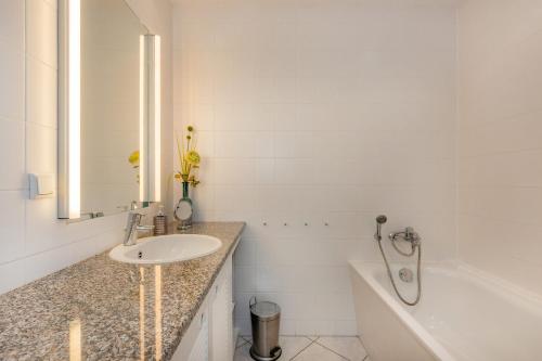 a white bathroom with a sink and a bath tub at Haus Dünenwald 17 in Zinnowitz
