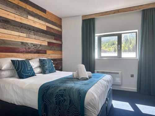a bedroom with a bed and a wooden wall at The Base Camp Hotel, Nevis Range in Fort William