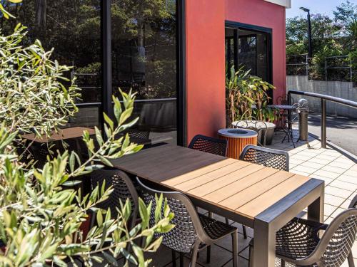 a wooden table and chairs on a patio with plants at ibis Thornleigh in Thornleigh