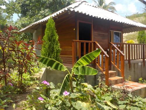 a small wooden cabin with a porch in a garden at Hostal Recuerdos del Tayrona in El Zaino