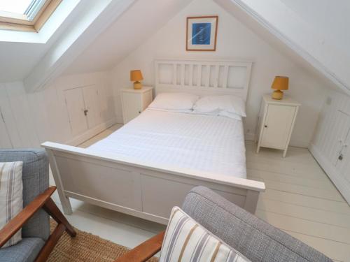 a bedroom with a white bed with two chairs at Badgers Loft in Penzance