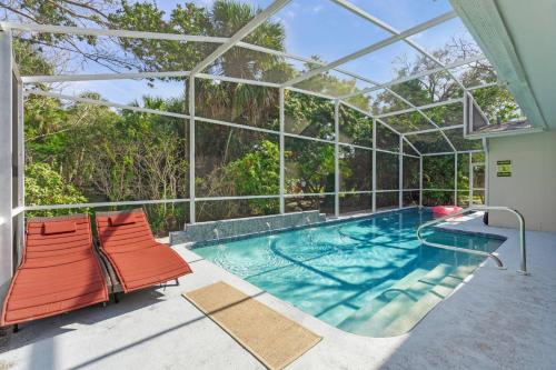 an indoor swimming pool with two chairs and a glass house at Toes in the Water - Pool Home on Siesta Key in Siesta Key