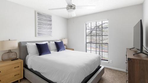 ein weißes Schlafzimmer mit einem Bett und einem Fernseher in der Unterkunft Landing Apartments - Denton in Denton