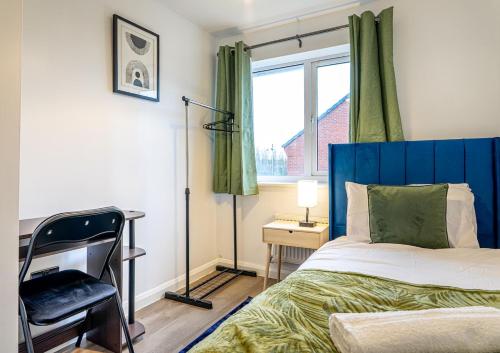 a bedroom with a blue bed and a desk and a window at Truvana Haven in Coundon