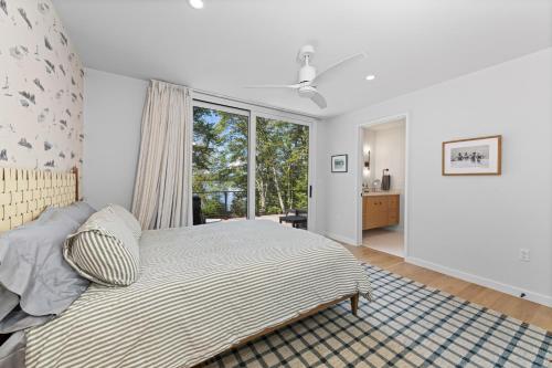 een slaapkamer met een bed en een groot raam bij NEW! Tilted Pine - Lake Access Modern Home in Center Harbor