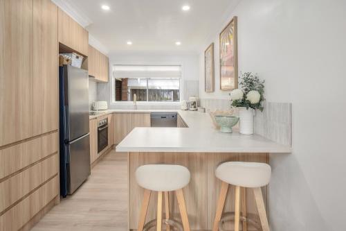 a kitchen with a large island with two white bar stools at 5 min walk to beach, 5 min drive to shops in Capel Sound