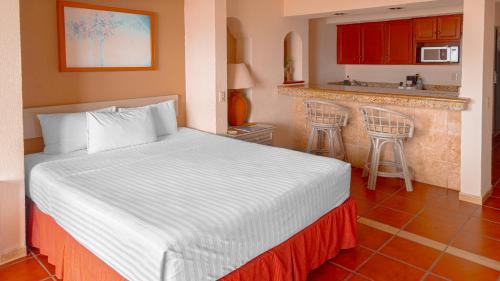 a bedroom with a large bed and a kitchen at The Palms Resort of Mazatlan in Mazatlán