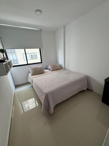 a white bedroom with a bed and two windows at APARTAMENTO Premium in Ibagué