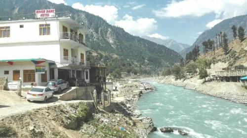 un bâtiment à côté d'une rivière à côté d'une montagne dans l'établissement Ghani Palace Hotel Kalam, à Kārandūkai