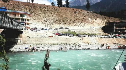 une rivière avec des voitures garées sur le côté d'une montagne dans l'établissement Ghani Palace Hotel Kalam, à Kārandūkai