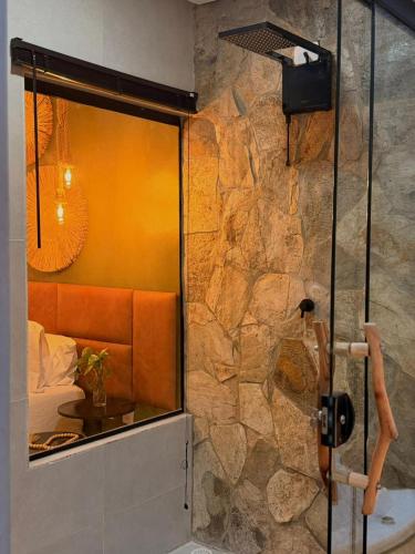 a bathroom with a shower with a stone wall at Pousada Alkamar in Maragogi