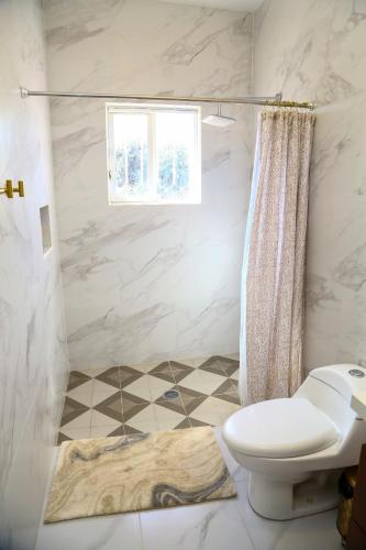 a white bathroom with a toilet and a window at Casa Naranja in Ciudad Fernández