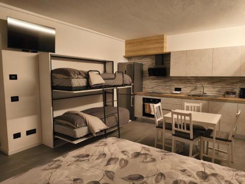 een kamer met een stapelbed, een tafel en een keuken bij Dimora Ananthèō in Tirano