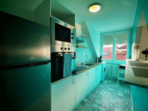 une cuisine avec des murs bleus et des armoires blanches dans l'établissement Baroquissime, à Dunkerque