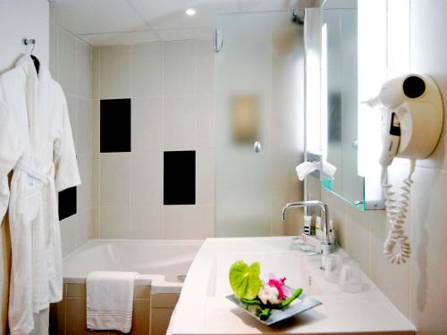 ein Badezimmer mit einer Badewanne und einem Waschbecken mit Blumen darauf in der Unterkunft Mercure Abbeville Centre – Porte de La Baie de Somme in Abbeville