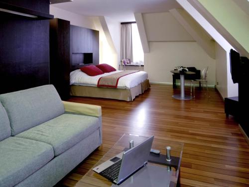ein Wohnzimmer mit einer Couch und einem Bett mit einem Laptop in der Unterkunft Mercure Abbeville Centre – Porte de La Baie de Somme in Abbeville