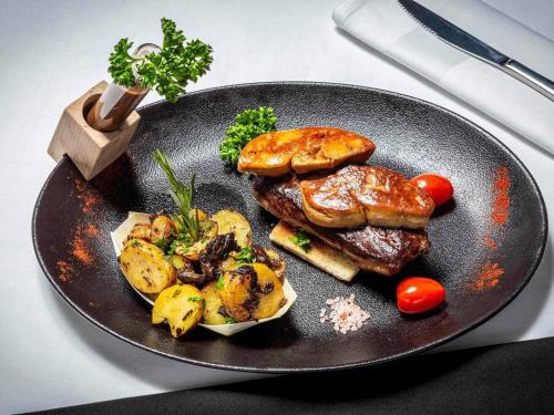 a plate of food with meat and vegetables on a table at Mercure Lourdes Impérial in Lourdes