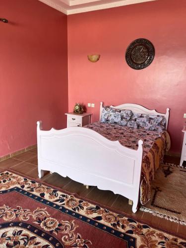 a bedroom with a white bed in a red wall at Beachfront villa sidi ouarzeg in Sidi Ouarsik