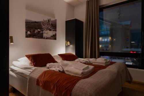 a bed with towels on it in a room with a window at Le Chalet Lingonberry D14 Ski-in Ski-out by Aavalevi in Levi