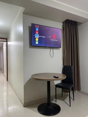 ein Raum mit einem Tisch und einem Fernseher an der Wand in der Unterkunft Agora Hs in Chincha