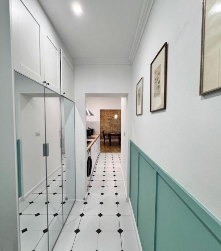 a hallway with green and white tile floors and white cabinets at Apartament na Starówce in Wałbrzych