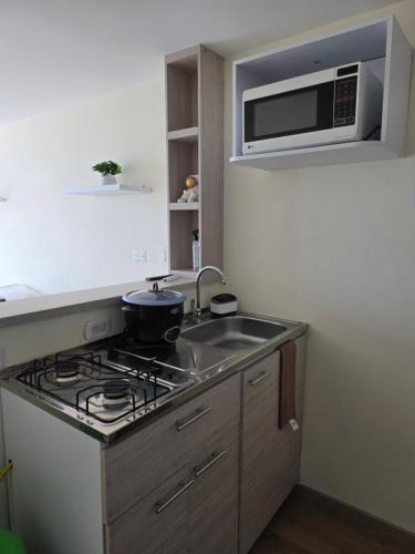 a kitchen with a stove and a sink and a microwave at Apartaestudio con vista a AV Santander Manizales in Manizales